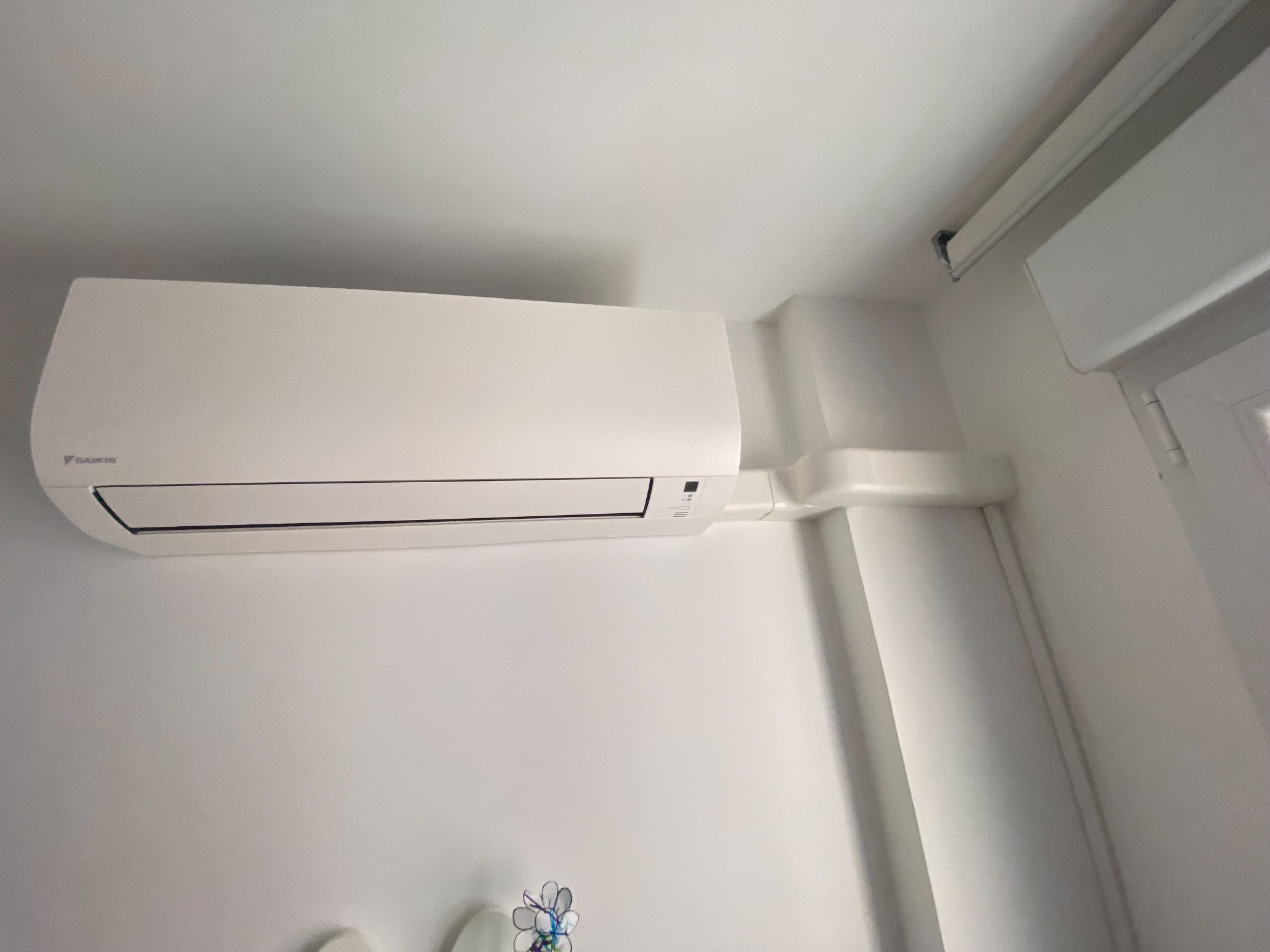 Unidad interior de aire acondicionado tipo split instalada en pared con canalización lateral.